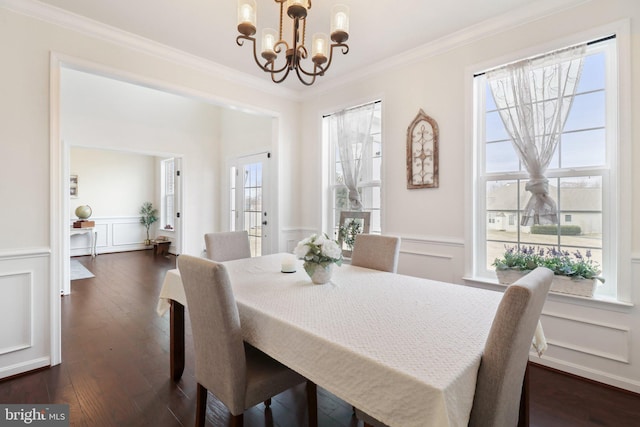 dining space featuring dark wood-style flooring, wainscoting, crown molding, and a decorative wall