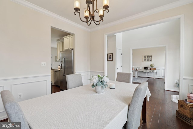 dining space featuring an inviting chandelier, ornamental molding, dark wood finished floors, and wainscoting