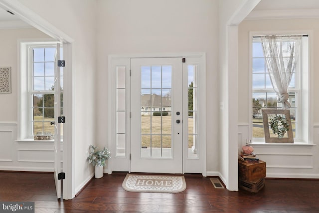 doorway to outside with plenty of natural light, visible vents, dark wood-style flooring, and ornamental molding