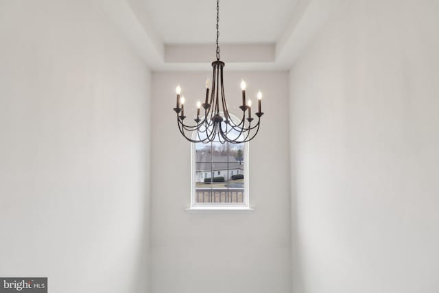 interior details featuring an inviting chandelier and a tray ceiling