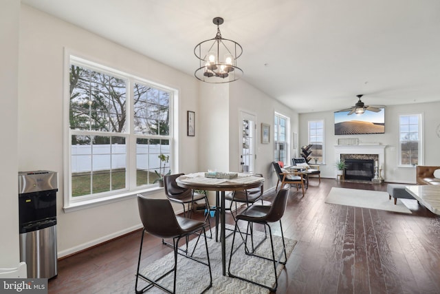 dining area featuring dark wood-style flooring, a fireplace, a wealth of natural light, and baseboards