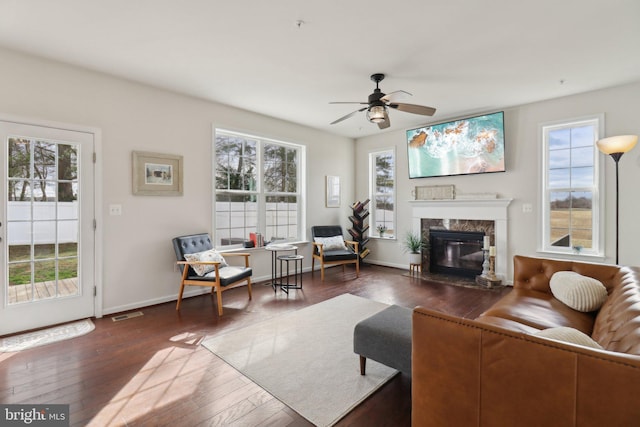 living room with ceiling fan, dark wood-type flooring, a premium fireplace, visible vents, and baseboards