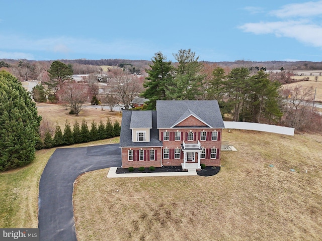 colonial inspired home featuring brick siding, aphalt driveway, and a front yard