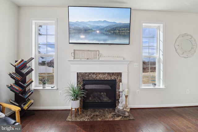 living room featuring wood-type flooring, baseboards, and a high end fireplace