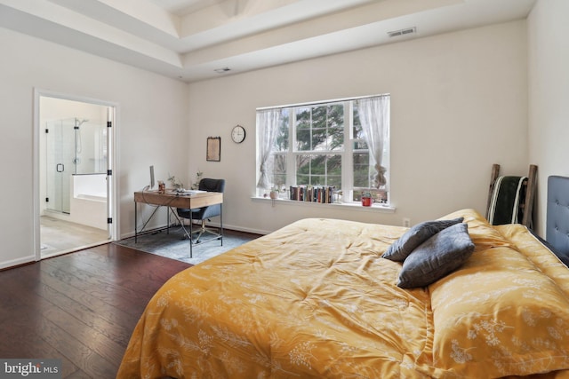 bedroom featuring a tray ceiling, visible vents, hardwood / wood-style floors, connected bathroom, and baseboards