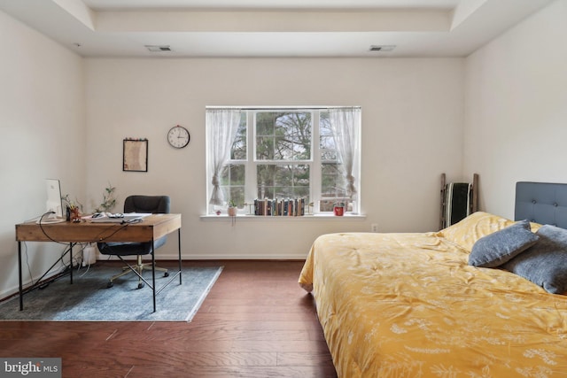 bedroom with hardwood / wood-style floors, visible vents, and baseboards