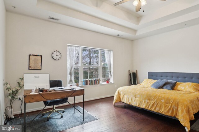 bedroom with baseboards, visible vents, a raised ceiling, and hardwood / wood-style floors