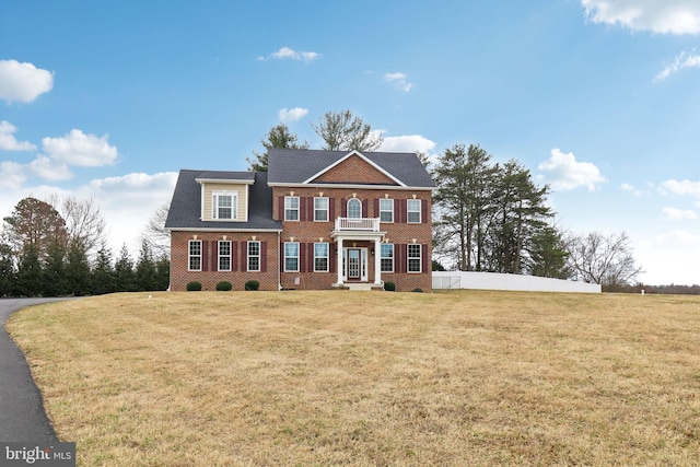 colonial house with brick siding, fence, and a front yard