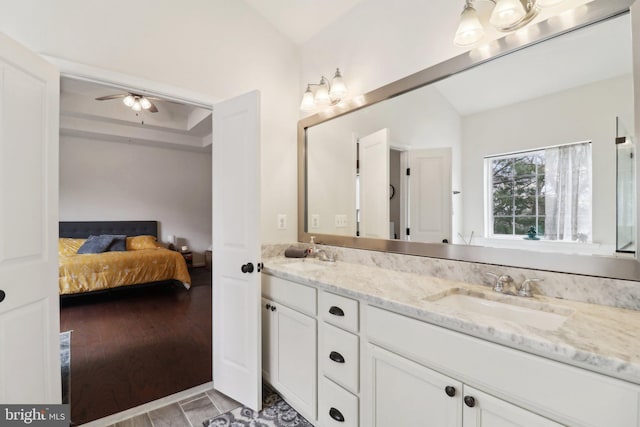 ensuite bathroom featuring double vanity, wood finished floors, ensuite bathroom, vaulted ceiling, and a sink