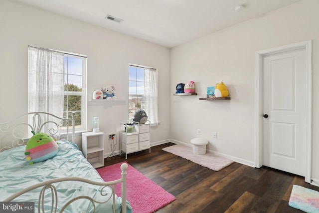 bedroom with visible vents, baseboards, and wood finished floors