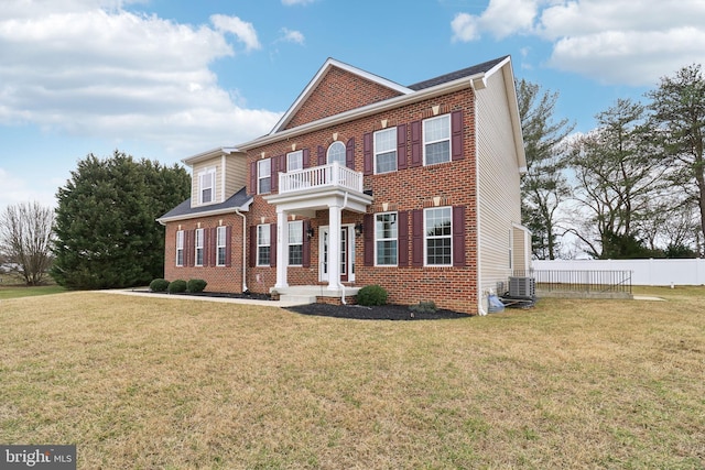 colonial home with a front yard, brick siding, fence, and a balcony