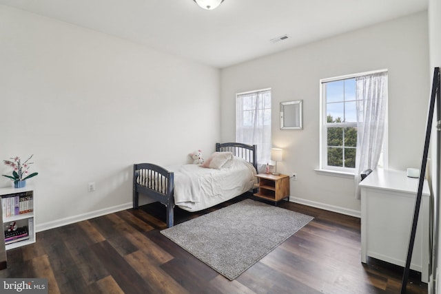 bedroom featuring wood finished floors, visible vents, and baseboards