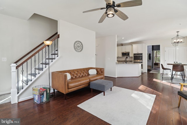 living area featuring recessed lighting, ceiling fan with notable chandelier, baseboards, stairs, and dark wood finished floors