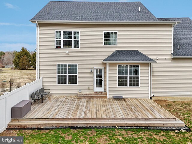 rear view of house featuring roof with shingles, fence, and a wooden deck