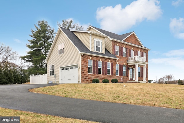 colonial inspired home with brick siding, an attached garage, fence, a balcony, and driveway