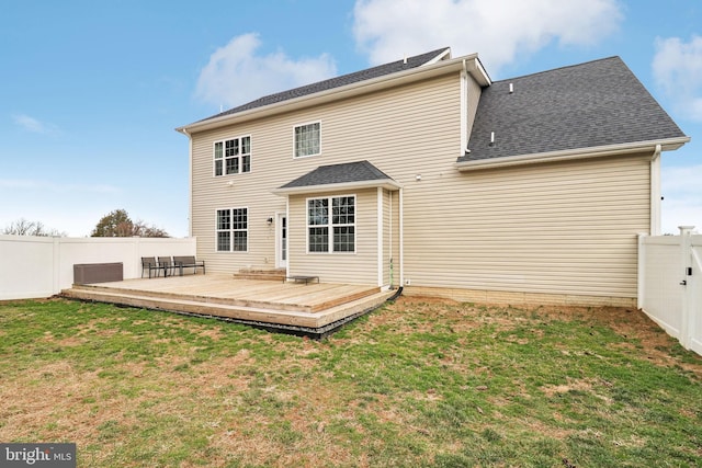 back of house with roof with shingles, a lawn, a fenced backyard, and a wooden deck