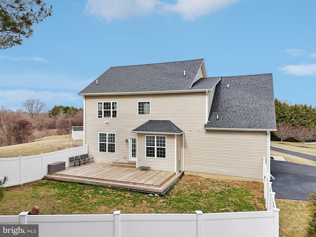 back of house featuring a fenced front yard, a shingled roof, and a wooden deck