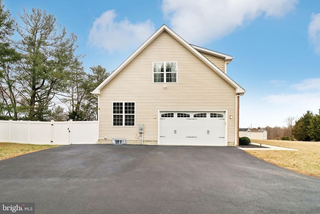 view of side of home featuring driveway, a gate, and fence