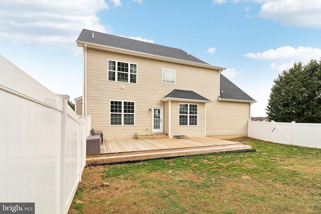 rear view of property featuring a fenced backyard, a gate, a wooden deck, and a yard