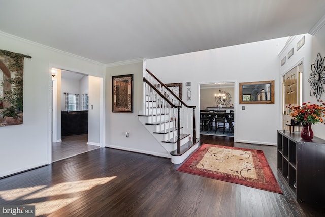 foyer entrance with crown molding, a notable chandelier, wood finished floors, baseboards, and stairs