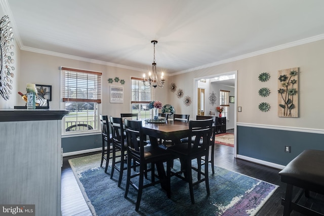 dining room featuring dark wood-type flooring, a chandelier, ornamental molding, and baseboards