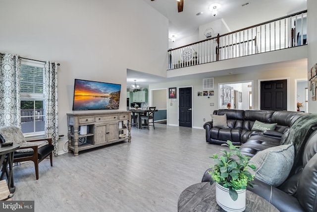 living area with visible vents, baseboards, wood finished floors, and ceiling fan with notable chandelier