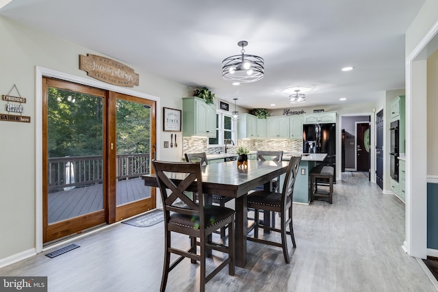 dining space with baseboards, visible vents, and light wood finished floors