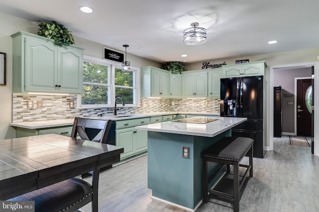 kitchen with light wood-style floors, a sink, a kitchen island, and black appliances