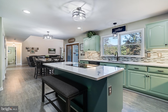 kitchen with a kitchen island, hanging light fixtures, a sink, and backsplash