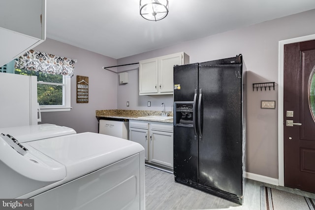 kitchen with white appliances, a sink, baseboards, light wood finished floors, and washer and clothes dryer