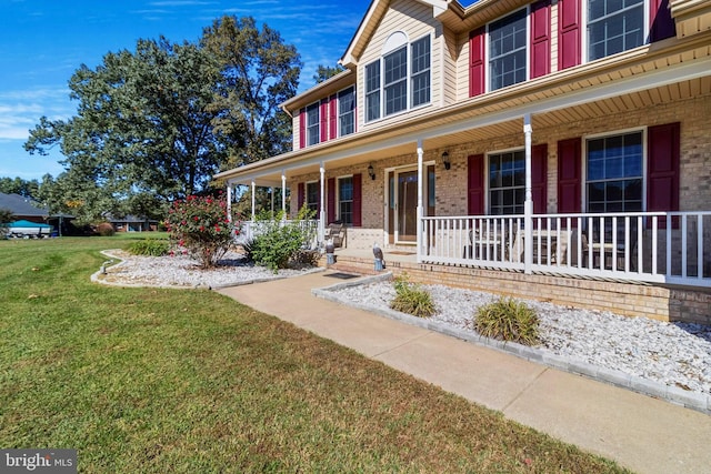 view of front of home with covered porch, brick siding, and a front lawn