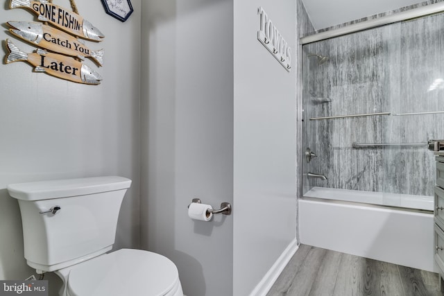 bathroom featuring enclosed tub / shower combo, toilet, and wood finished floors