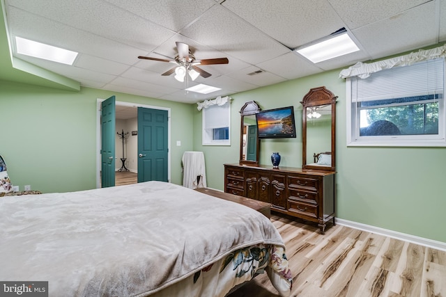 bedroom with a paneled ceiling, wood finished floors, visible vents, and baseboards