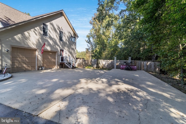 view of property exterior featuring concrete driveway and fence