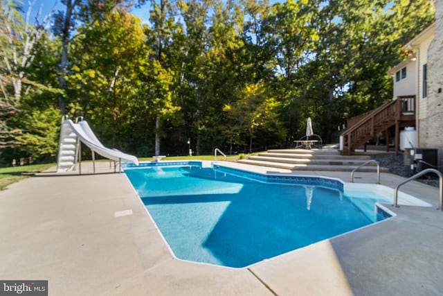 outdoor pool featuring a patio, a water slide, and stairway