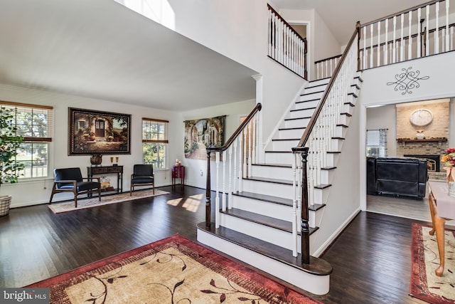 foyer entrance with a brick fireplace, a high ceiling, baseboards, and hardwood / wood-style floors