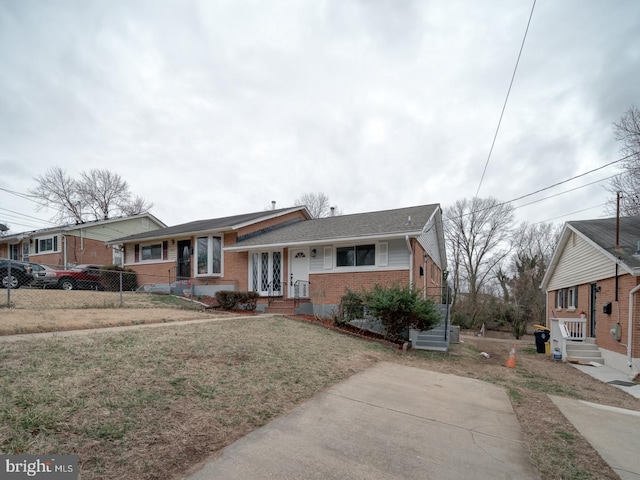 view of front of house with brick siding, fence, and a front lawn