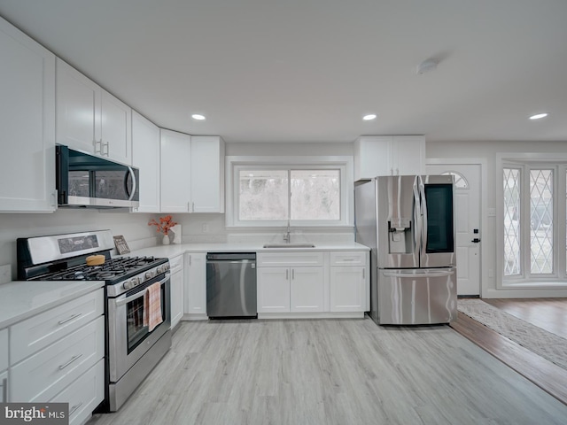 kitchen featuring recessed lighting, a sink, white cabinets, appliances with stainless steel finishes, and light wood-type flooring