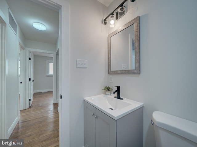 bathroom featuring baseboards, vanity, toilet, and wood finished floors