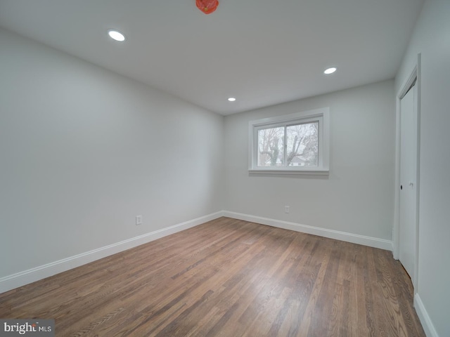 unfurnished bedroom with a closet, recessed lighting, wood finished floors, and baseboards