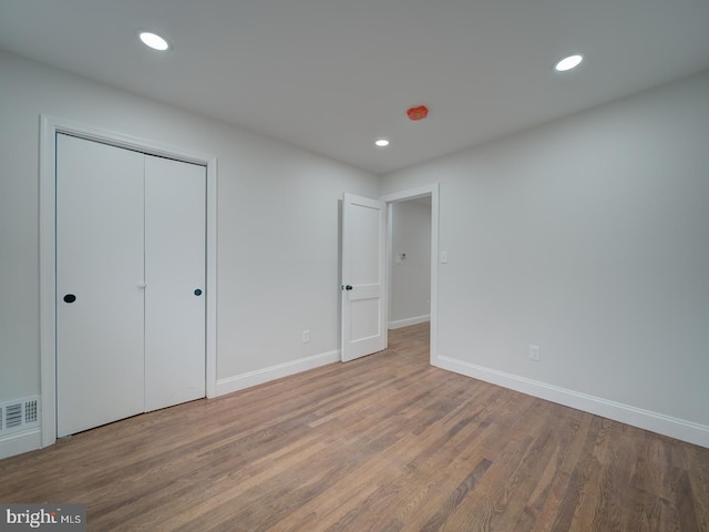 unfurnished bedroom featuring baseboards, wood finished floors, visible vents, and recessed lighting