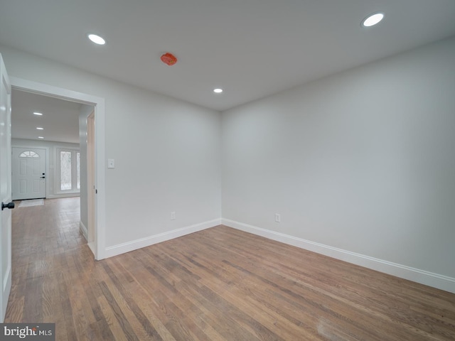 spare room with baseboards, wood finished floors, and recessed lighting