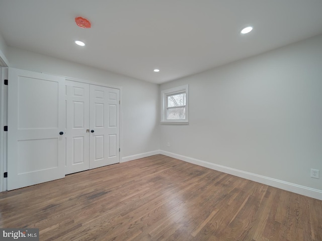 unfurnished bedroom featuring recessed lighting, a closet, baseboards, and wood finished floors