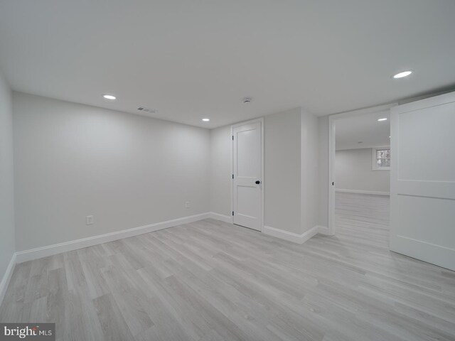 finished below grade area with recessed lighting, light wood-type flooring, visible vents, and baseboards