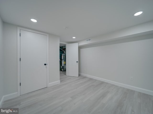 finished basement featuring gas water heater, recessed lighting, visible vents, light wood-type flooring, and baseboards