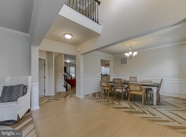 dining room featuring an inviting chandelier, parquet floors, crown molding, and visible vents