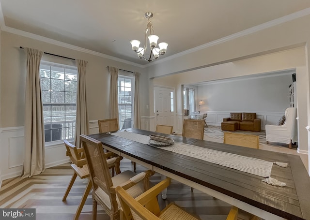 dining area with a decorative wall, ornamental molding, a wainscoted wall, and a chandelier