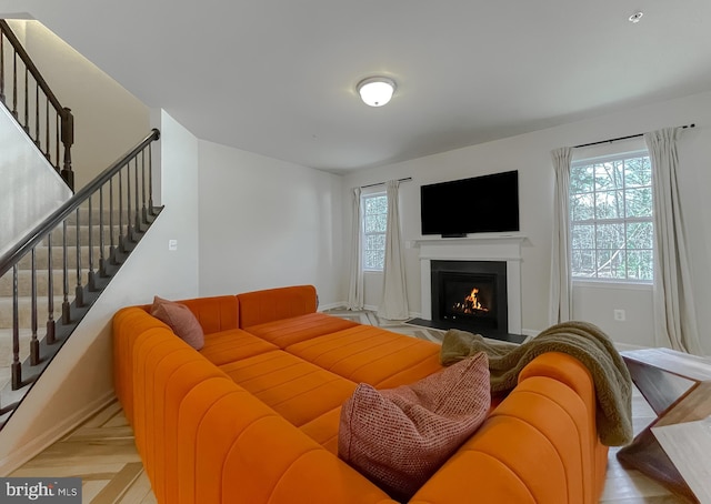 living room featuring stairs, plenty of natural light, baseboards, and a fireplace with flush hearth