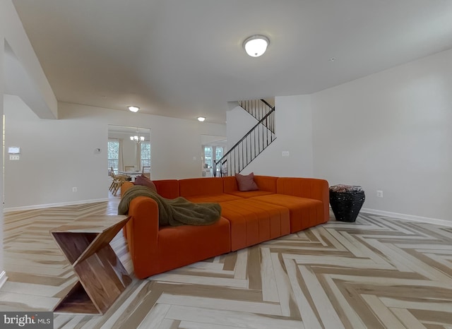 living area featuring an inviting chandelier, stairs, and baseboards