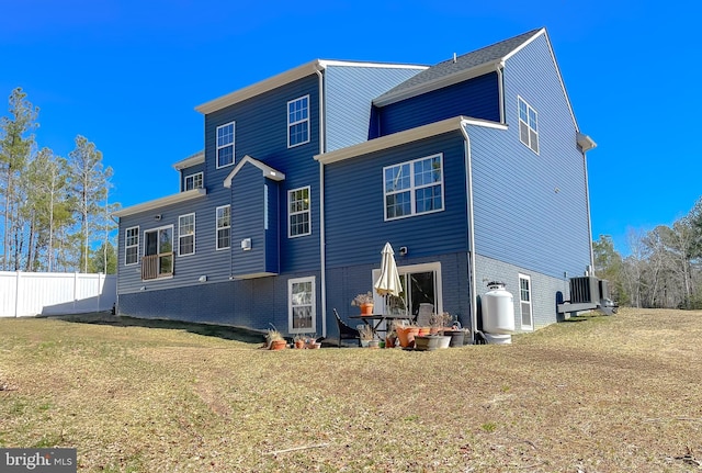 rear view of house featuring central AC unit, fence, brick siding, and a lawn